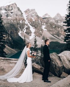 a bride and groom standing on top of a mountain