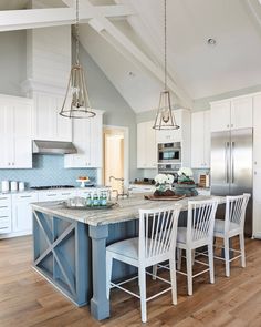 a kitchen with white cabinets and blue island