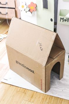 a cardboard dog house sitting on top of a wooden floor