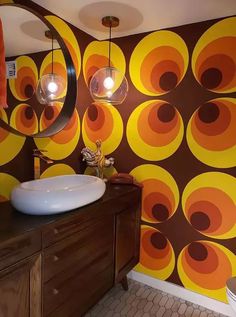 a bathroom with an orange and brown wallpaper, round lights and a white sink