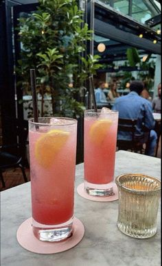 two glasses filled with pink liquid sitting on top of a table next to each other