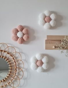 three small white and pink pom poms on a wall next to a mirror