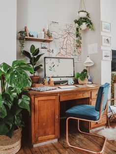 a desk with a computer on top of it next to a large potted plant