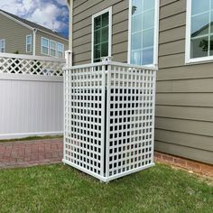 a large white trellis sitting on top of a grass covered yard next to a house