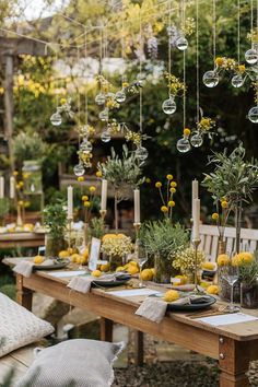 an outdoor dining table with lemons and greenery hanging from it's ceiling