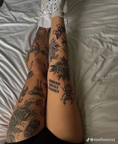 a woman laying on top of a bed with tattoos on her legs and leggings