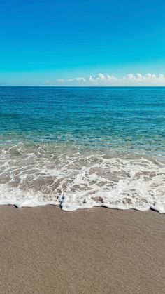 an ocean view with waves coming in to the shore and blue sky above, on a sunny day