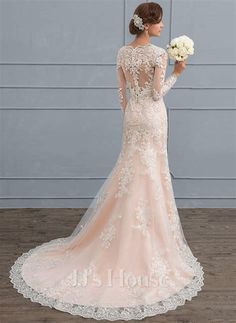 a woman in a wedding dress standing on a wooden floor with her back to the camera