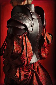 the back of a woman's dress with leather armor and red lace on it