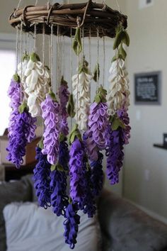 purple and white flowers are hanging from a wicker chandelier in a living room