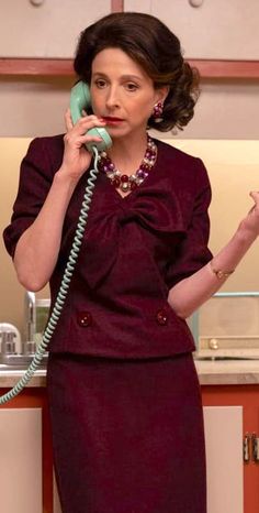 a woman talking on a phone while standing in a kitchen