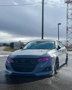 the front end of a silver car parked in a parking lot next to a light pole