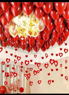 red heart balloons hanging from the ceiling with love written on them and other decorations below