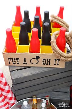 a crate filled with red and black bottles sitting on top of a wooden table next to other items