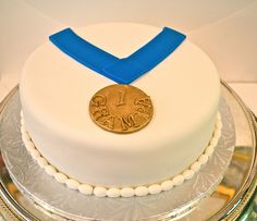 a white cake with blue ribbon and gold medal on top