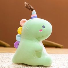 a green stuffed animal with a party hat on it's head sitting on a table