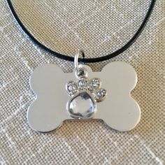 a dog's paw and heart shaped bone pendant on a black leather cord necklace