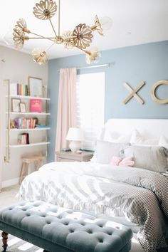 a bedroom with blue walls, white bedding and a chandelier hanging from the ceiling