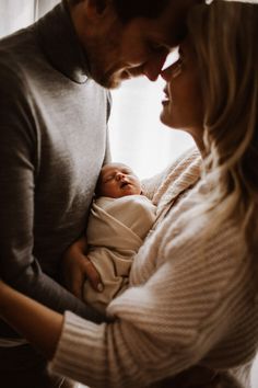 a man and woman holding a baby in their arms