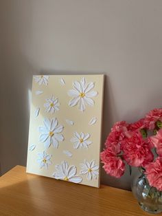 a vase filled with pink and white flowers next to a painting