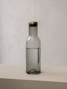 a glass bottle sitting on top of a white counter next to a metal object with a gold cap