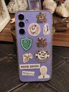 a cell phone with many different stickers on it's back cover sitting on a table