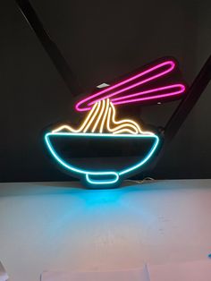 a neon sign that has noodles in a bowl on top of it with chopsticks sticking out of it