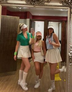 three women in tennis outfits taking a selfie with their cell phones while standing in front of a mirror