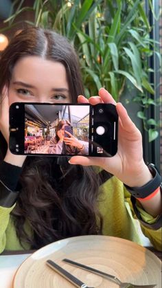 a woman taking a selfie with her cell phone in front of her at a restaurant