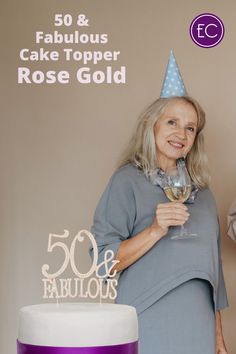 a woman holding a wine glass in front of a cake with the words 50 and fabulous on it