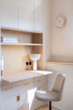 a chair sitting in front of a desk with a clock on the wall behind it