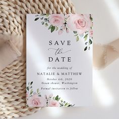 wedding save the date card with pink roses and greenery on it, next to a wicker basket