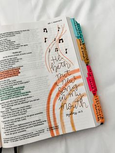 an open bible with handwritten notes on the page and colored pencils next to it