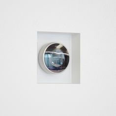 an electronic device mounted on the side of a white wall with a circular window in it