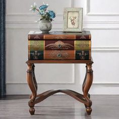 a small wooden table with a vase and flowers on it