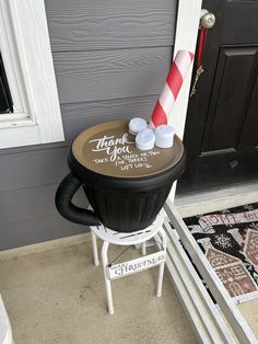 a candy cane sitting on top of a trash can in front of a door that says thank you