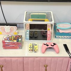 a table topped with toys and electronics on top of a white counter next to a tv