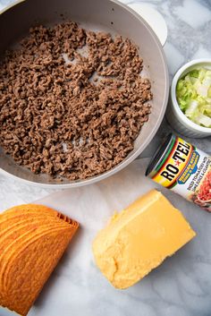 cheese, meat and other ingredients are on the counter next to a bowl of soup