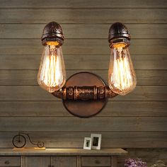 two light fixtures mounted on the side of a wall next to a dresser and table