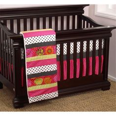 a baby crib with pink, black and white bedding on the bottom half