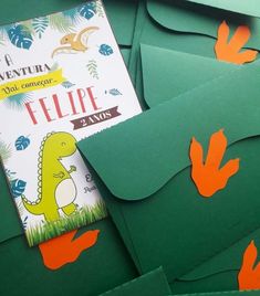 green envelopes with orange handprinted dinosaurs on them and a book in the middle