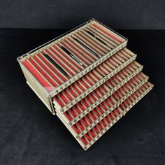 a stack of red and black books sitting on top of each other in front of a black background