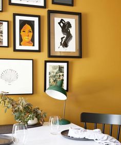 a dining room with yellow walls and pictures on the wall