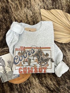 How adorable is this Coors Cowboy design!?! Perfect for everyday wear! This will be your new go to crewneck this spring/summer! Printed on unisex fit Ash crewneck Made to order, please allow up to 6 days for create time MADE TO ORDER JUST FOR YOU —FINAL SALE ITEM Country Crewneck, Cheap Country Style Crew Neck T-shirt, Coors Light Sweatshirt, Crew Neck T-shirt For Country Concerts, Cowboy Crewneck, Cowboy Design, White Crewneck, Everyday Wear, Cowboy