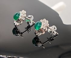 These enchanting stud earrings showcase round-shaped green onyx gemstones set in a lustrous sterling silver flower motif. The exquisite green hue of the onyx stones adds a fresh and vibrant touch to the floral design, reminiscent of a blossoming garden. Each earring features a central green onyx gemstone, carefully cut and polished to enhance its natural beauty. The smooth surface of the gemstones reflects light, highlighting their unique color variations and creating a mesmerizing visual effect. The sterling silver flower setting adds a delicate and feminine touch to the earrings. The intricate detailing of the petals and the overall craftsmanship of the design make these earrings a true work of art. Green Sterling Silver Flower-shaped Earrings, Green Flower Earrings For Pierced Ears, Black Tourmaline Bracelet, Citrine Earrings, Tourmaline Bracelet, Garnet Bracelet, Flower Motif, Onyx Gemstone, Sterling Silver Flowers