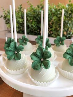 some white cake pops with green flowers on them and candles in the middle are sitting on a plate