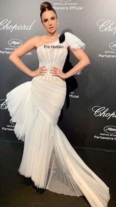 a woman in a white dress standing on a black and white carpet with her hands on her hips