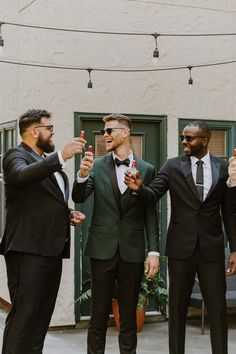 three men in tuxedos are standing together and holding their hands up to the camera