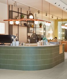 the interior of a restaurant with green tiled counter tops and lights hanging from the ceiling