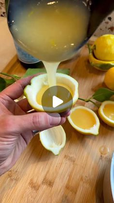 someone is pouring something into a bowl with lemons